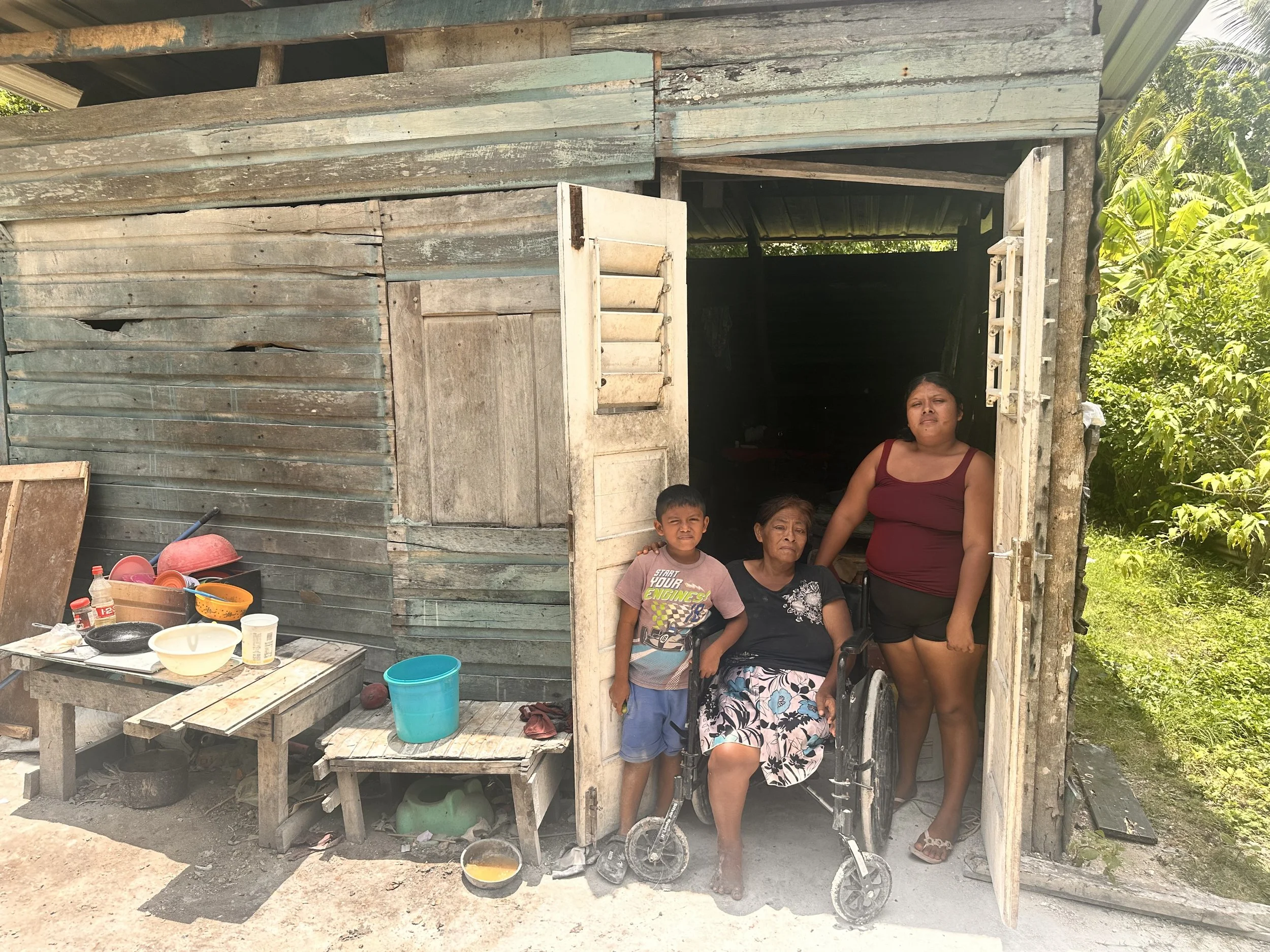 True Belize volunteers provide food assistance and prayer to a widow, her daughter, and grandson in Caledonia Village, Corozal District, Belize.