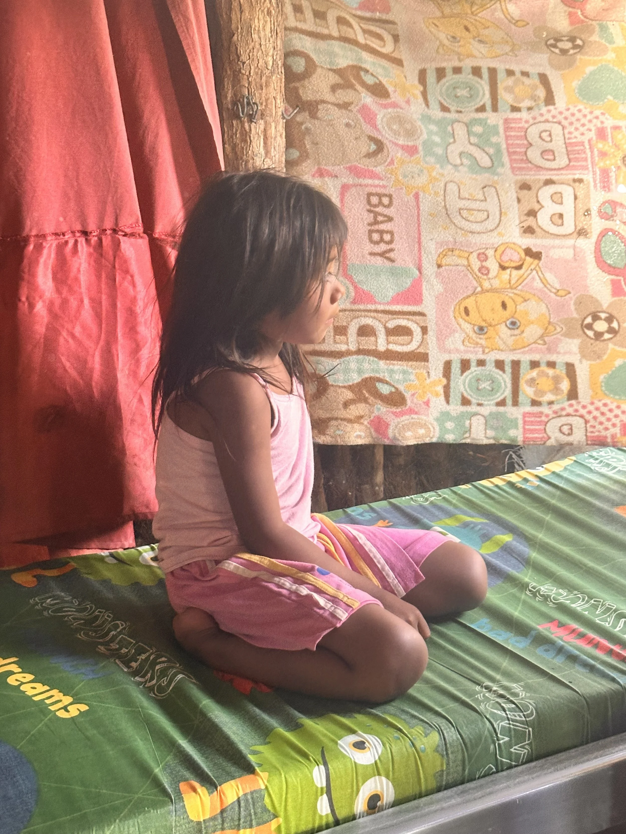 Young girl receiving a handmade bunk bed from True Belize in Caledonia Village, Corozal District, Belize.