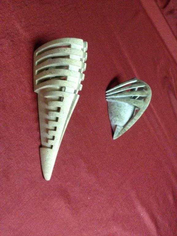 Zwei geteilte Scoop-Siebe aus Metall auf einem roten Stoffhintergrund.