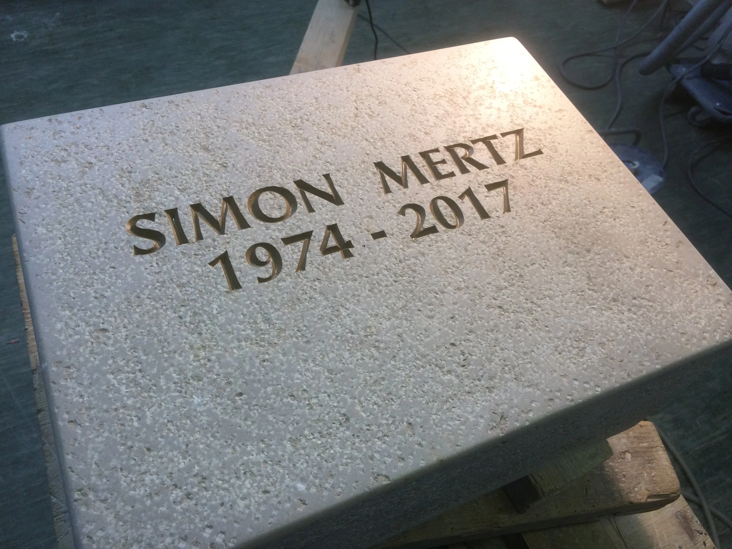 Grabstein mit eingravierten Namen "Simon Mertz", Jahren 1974 bis 2017, aus hellem Stein.