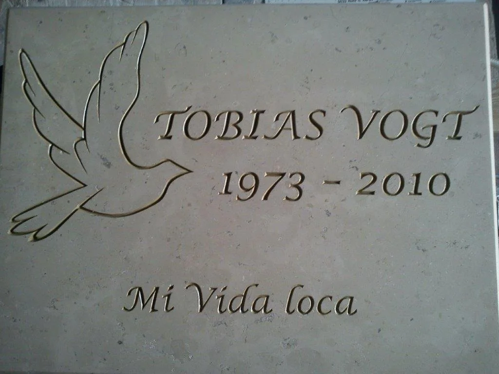 Gedenktafel mit einer geflügelten Taube, Name Tobias Vogt, Jahre 1973 bis 2010, und dem Spruch "Mi Vida Loca".