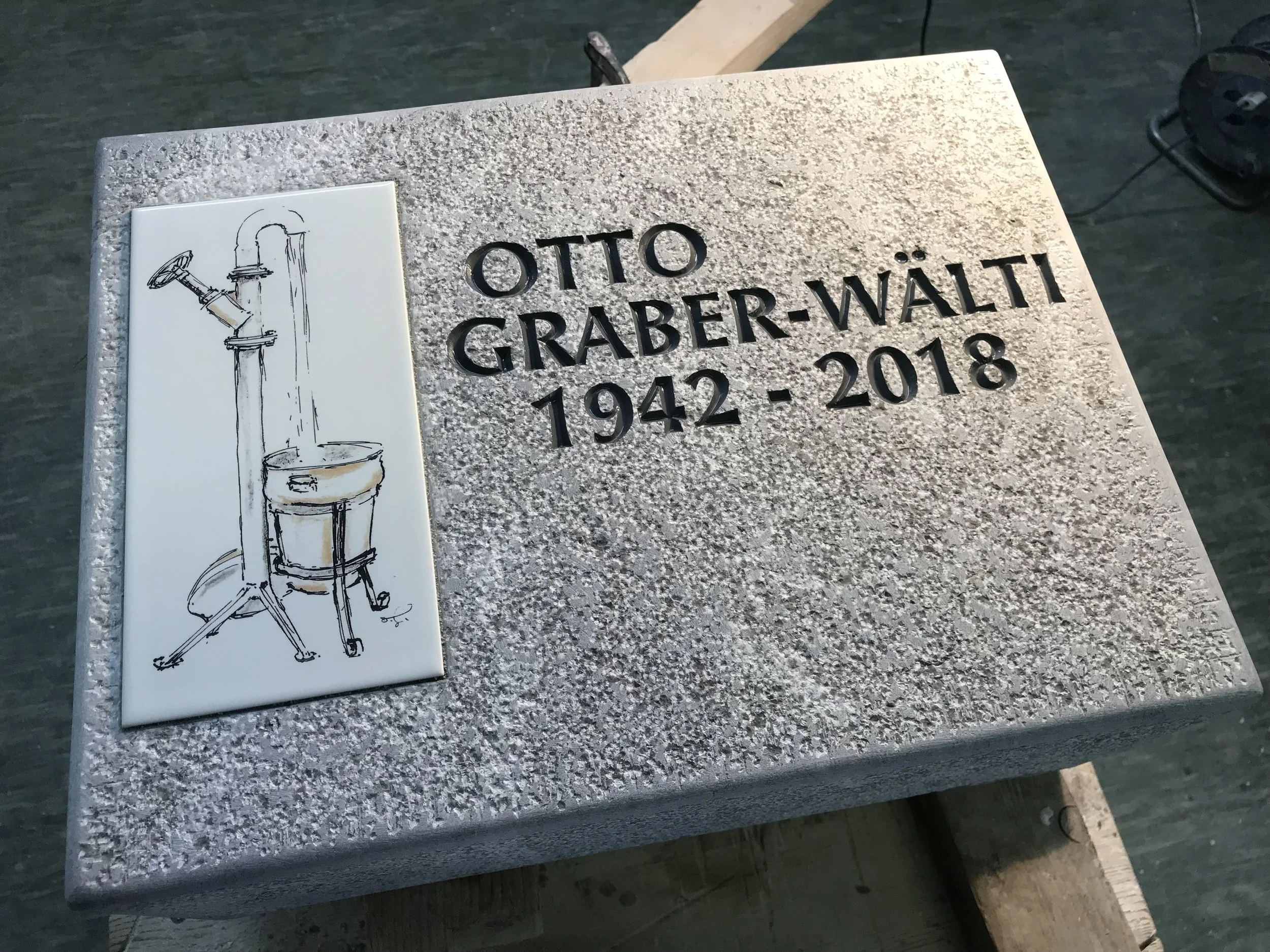 Gedenktafel mit Name und Lebensdaten von Otto Graber-Wältli und einer Zeichnung eines Wasserhahns mit Wasserkrug.