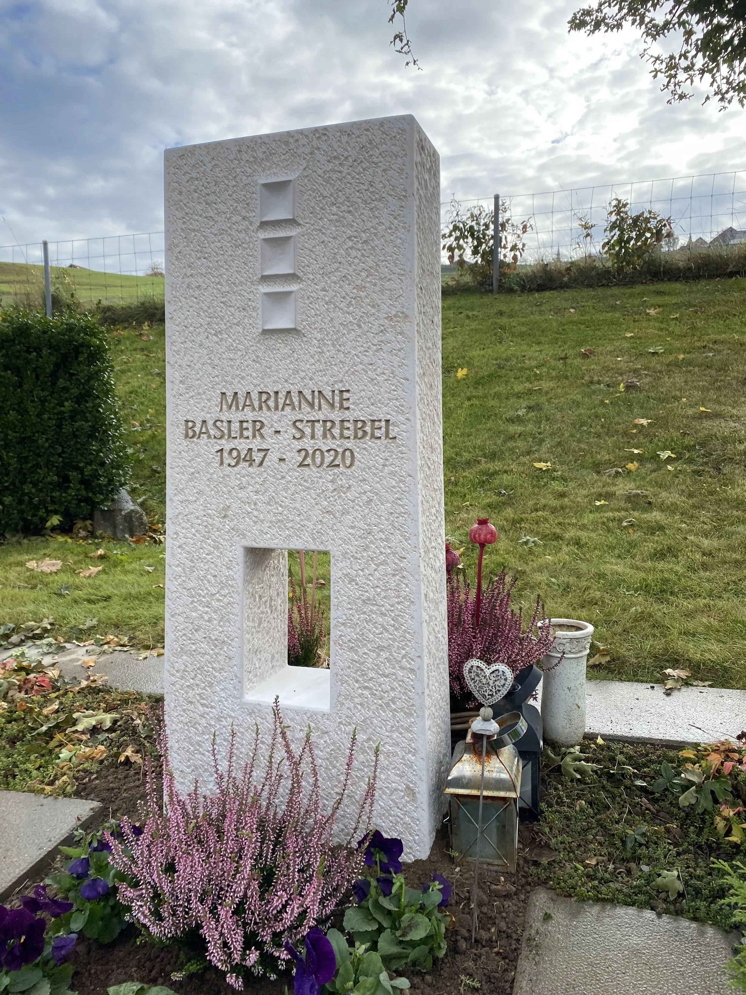 Gedenkstein mit Namen Marianne Basler-Srebel, Geburtsjahr 1947, Sterbejahr 2020, im Garten mit Blumen, Laterne und Dekorationen.