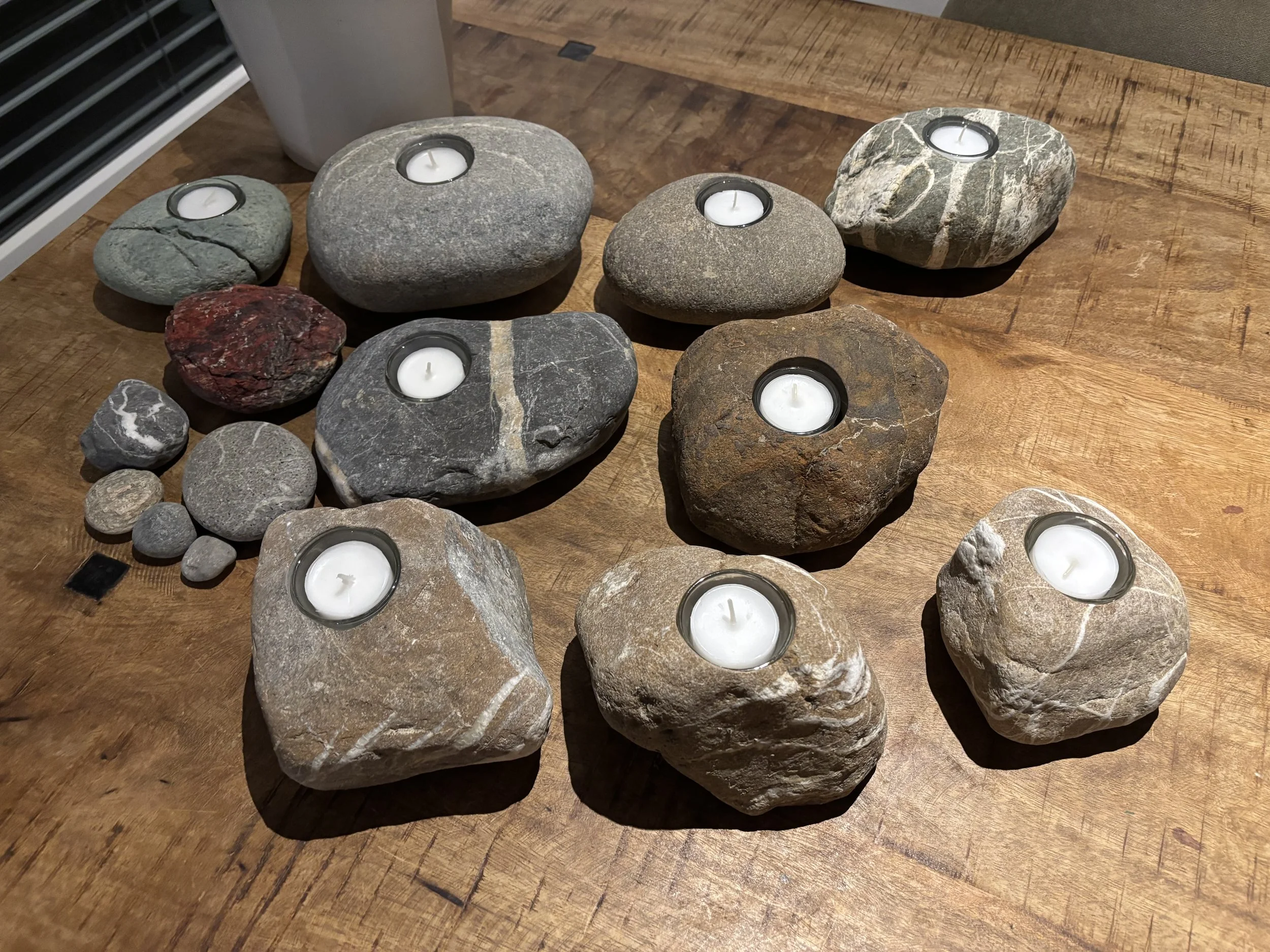 Verschiedene Steine mit Teelichtern auf einem Holztablett
