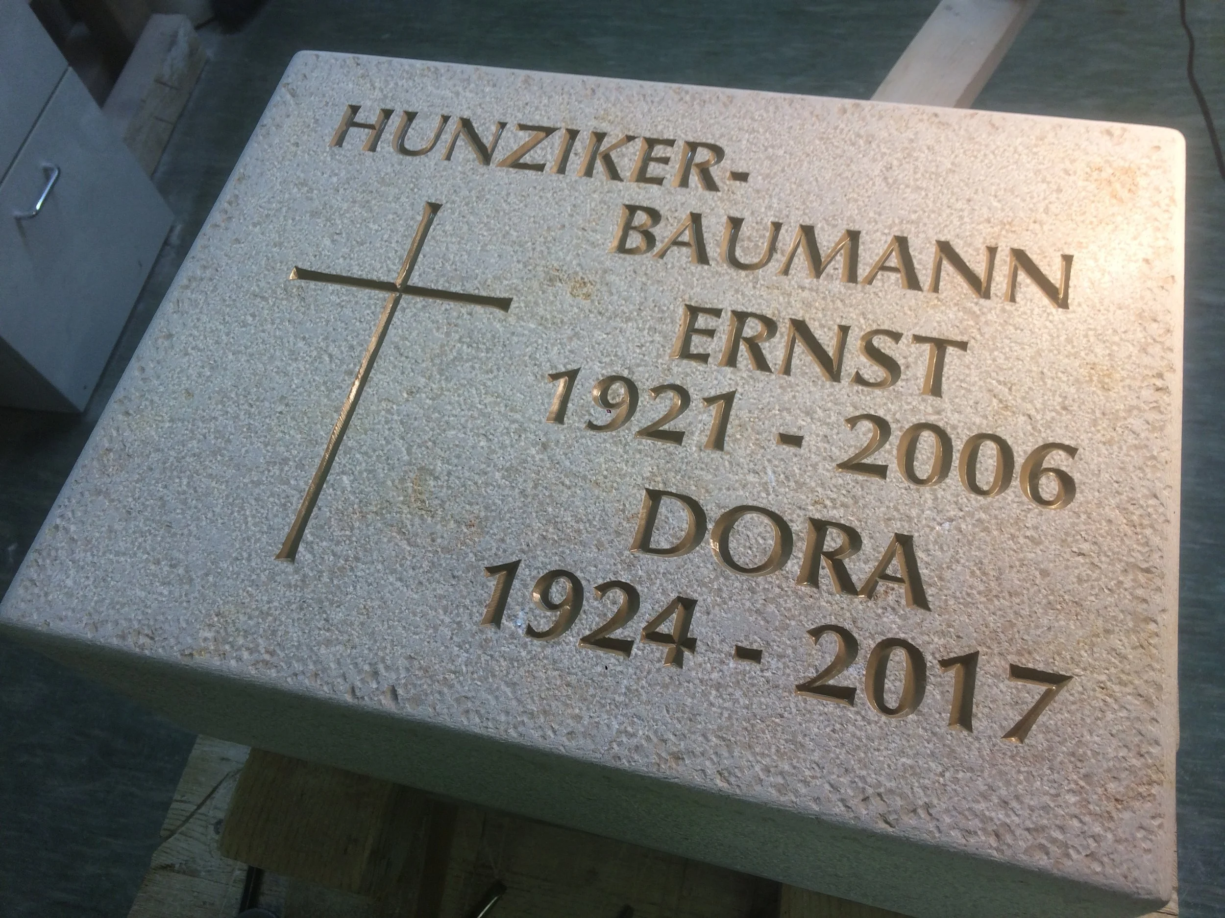 Grabstein mit Gravur für Ernst Hunziker-Baumann und Dora, mit Kreuzsymbol.