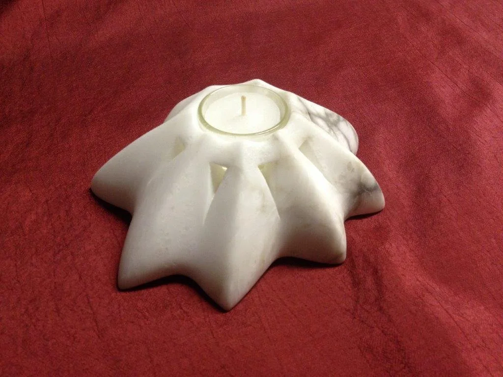 Weißer Kerzenhalter in Form eines Sterns auf rotem Tisch.