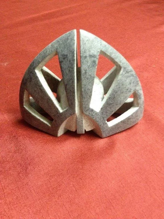 Ein dekoratives Objekt, das wie das Emblem von Darth Vader aus Star Wars aussieht, auf einem roten Stoffhintergrund.