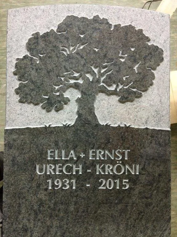 Grabstein mit einem gravierten Baum und den Namen Ella und Ernst Urech - Kröni, geboren 1931, verstorben 2015.