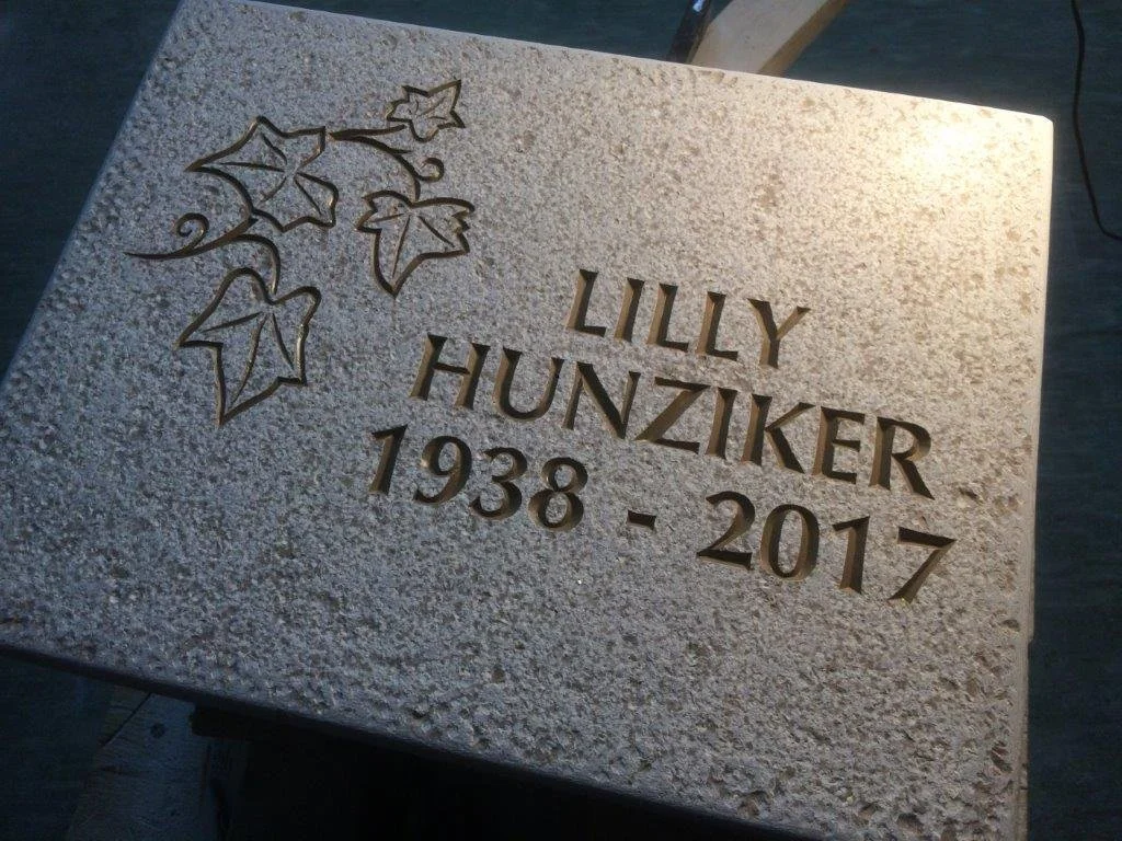 Grabstein mit eingravierten Lindenblättern, Namen Lilly Hunziker und den Lebensdaten 1938 bis 2017.
