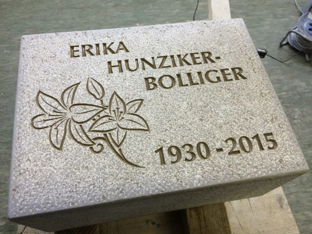 Ein Grabstein für Erika Hunziker-Bolliger, mit Blumenrelief und den Jahren 1930-2015.