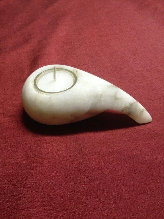 Eine Muschel mit einer Kerze darin liegt auf einem roten Tuch.