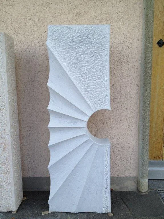 Ein skulpturales Kunstwerk in Form eines weißen, modernen Spiral-Designs, das an eine aufgefächertes Objekt erinnert.