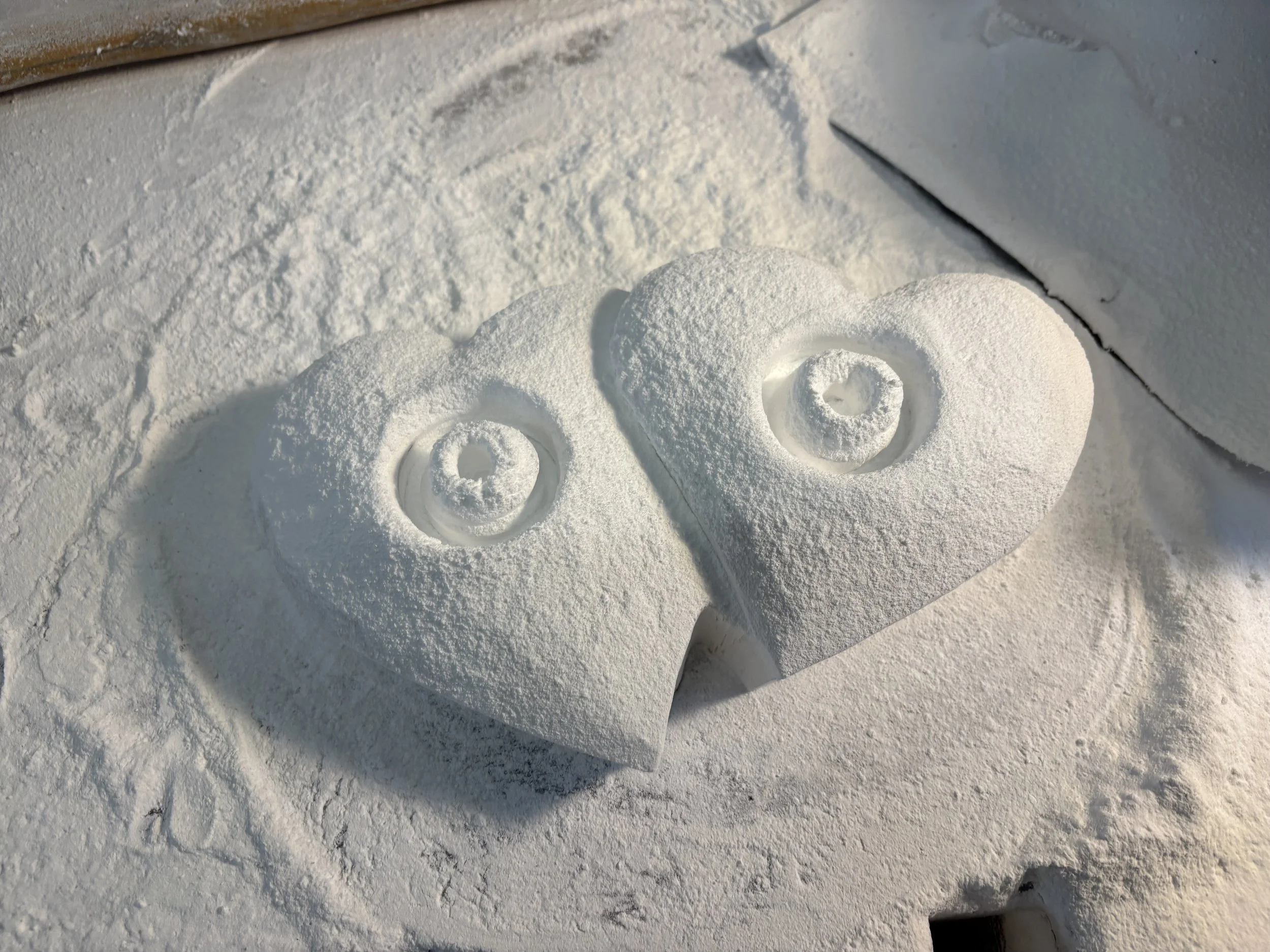 Herzförmige Schneefiguren mit Kreis Muster in der Mitte, auf Schnee liegend.