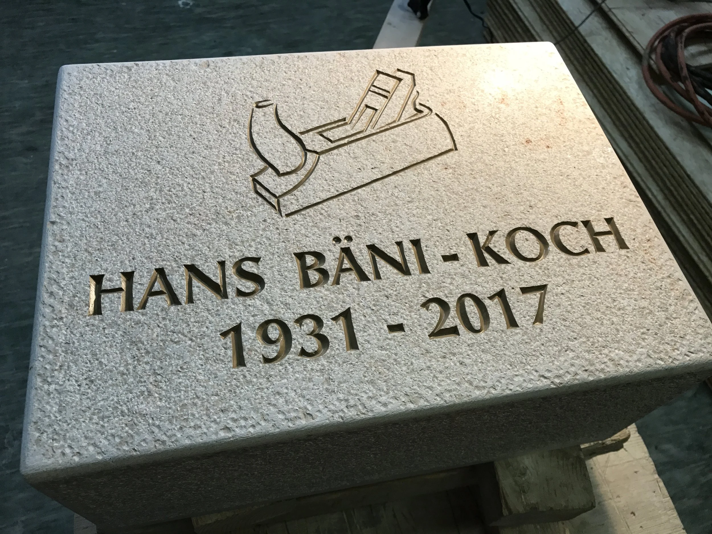 Grabstein mit graviertem Schneidebrett, Messer, Birne und Text: Hans Bäni-Koch, 1931-2017.