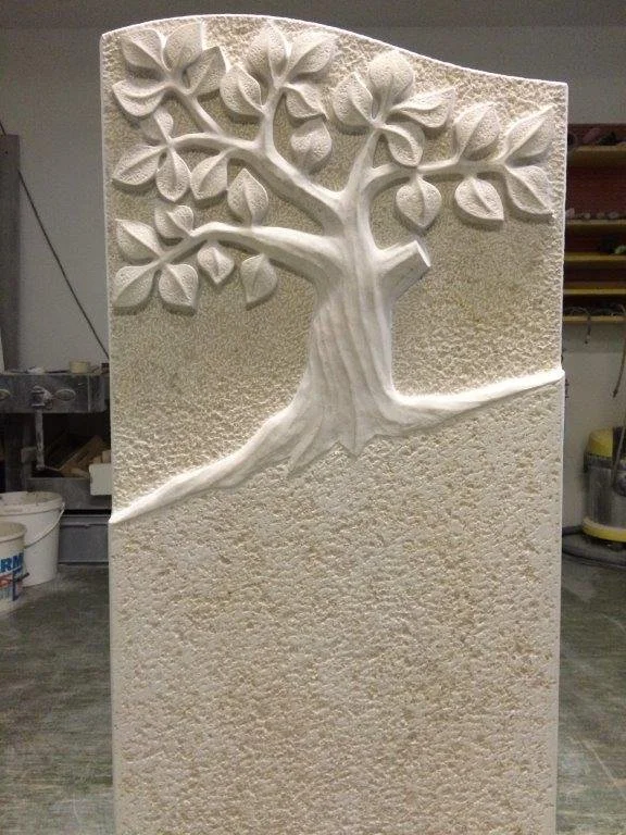Relief eines Baumes mit Blättern auf einer weißen Steinskulptur
