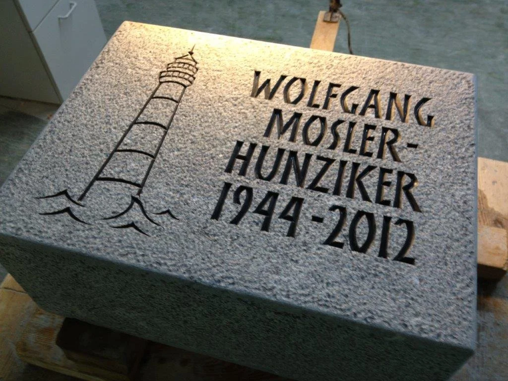 Gedenktafel mit Aufschrift für Wolfgang Mosler-Hunziker, 1944-2012, und einer eingezeichneten Leuchtturm auf Wasser.