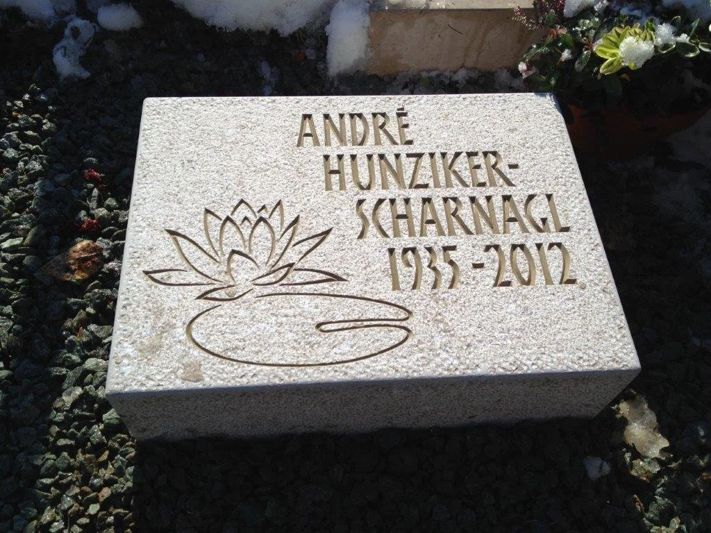 Grabstein mit eingestanztem Wasserlilie-Design und den Namen André Hunziker-Scharngal, gestorben 2012, geboren 1955.