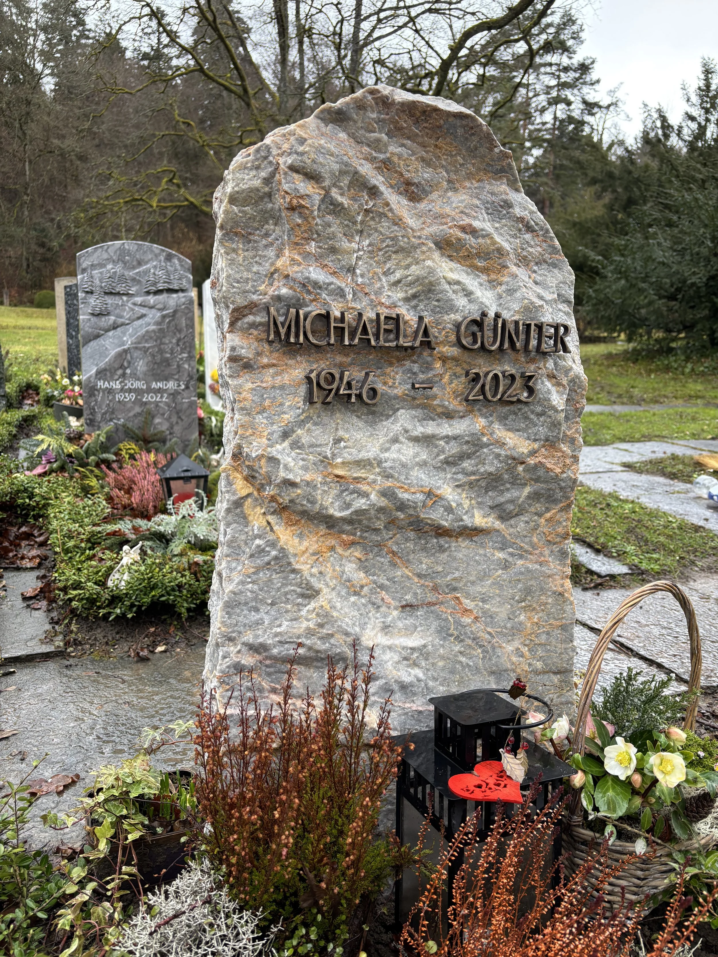 Grabstein mit eingraviertem Namen "Michaela Günter" und den Jahren 1946 bis 2023, umgeben von Blumen und Dekorationen in einem Friedhof.