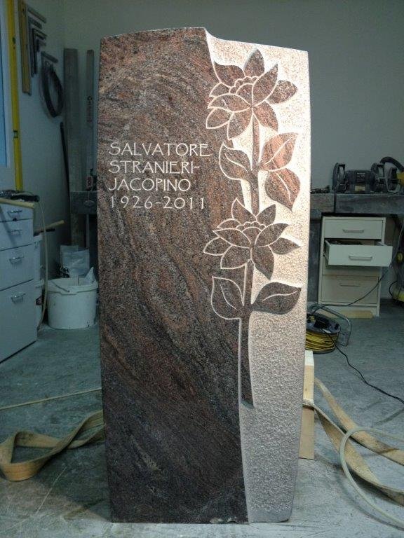 Ein Grabstein aus poliertem Granit mit einer eingeätzten Rose und den Namen Salvatore Stranieri-Jacopino (1926-2011).