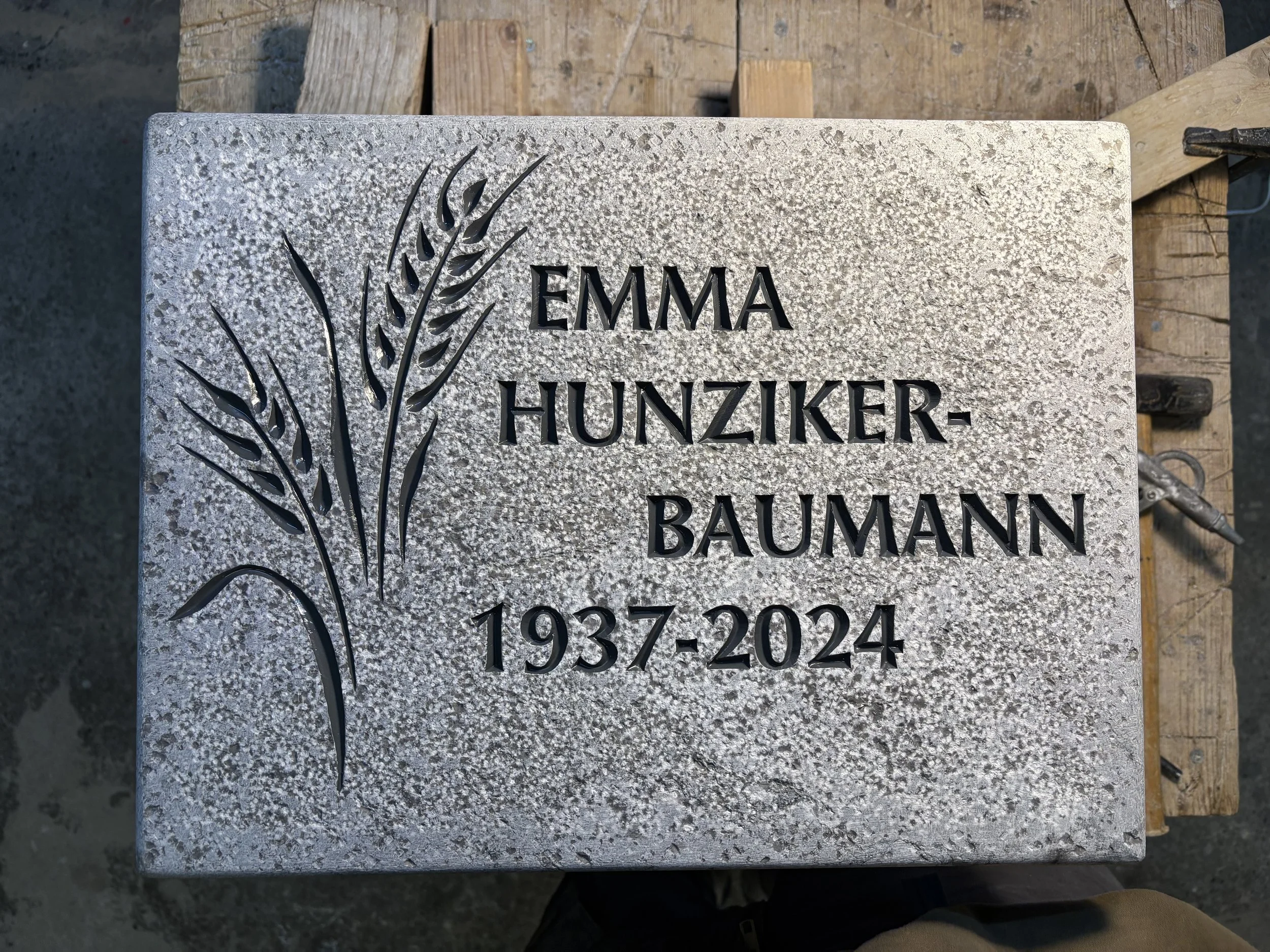 Grabstein mit eingelegtem Namen Emma Hunziker-Baumann und den Jahren 1937 bis 2024, mit einer Gravur von Getreideähren