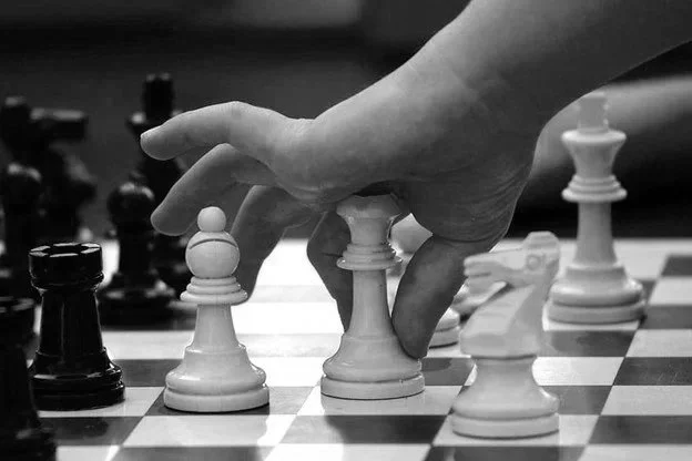 Close-up of a hand moving a white rook on a chessboard during a game.