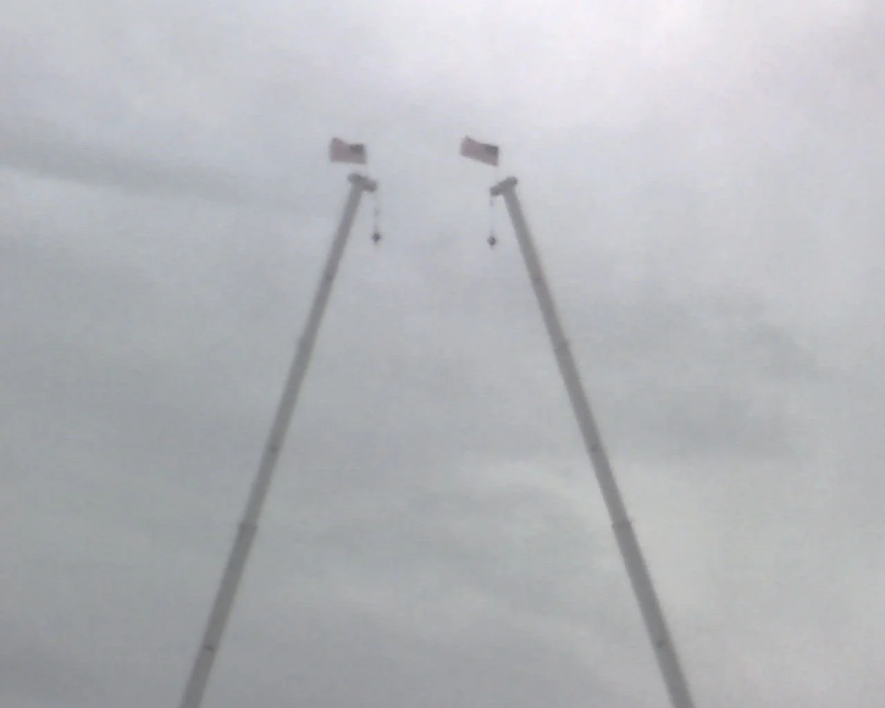 Suspended ski lift chairs against a cloudy sky.