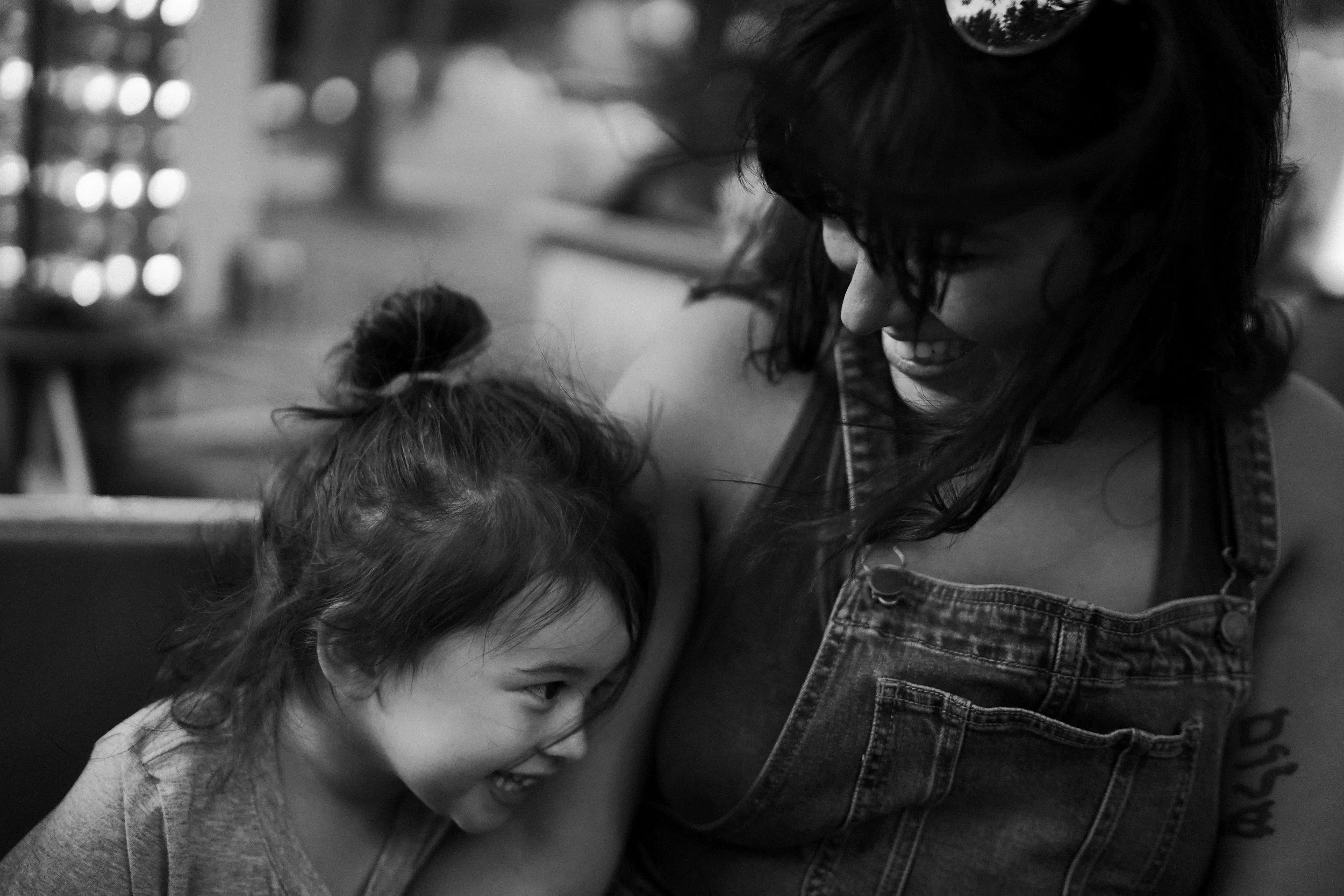 Black-and-white candid photo of a mother smiling with her preschool-aged child