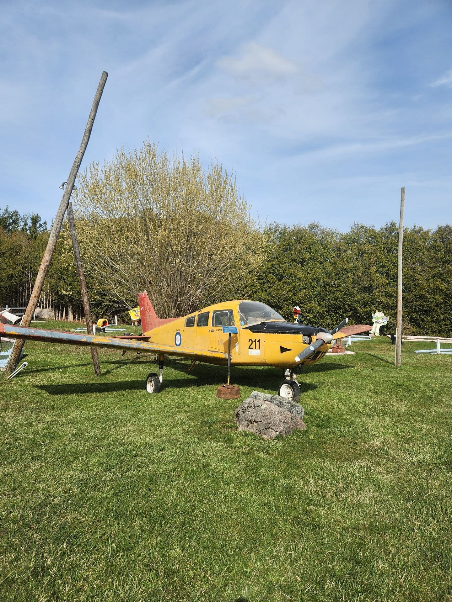 A small yellow and black airplane on display at an outdoor mini putt course.