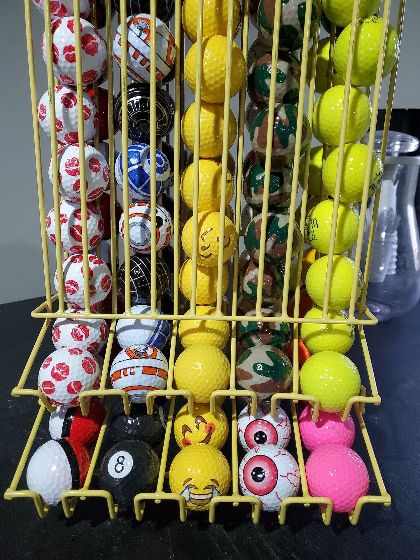 A yellow wire basket filled with various colorful mini putt golf balls arranged vertically.