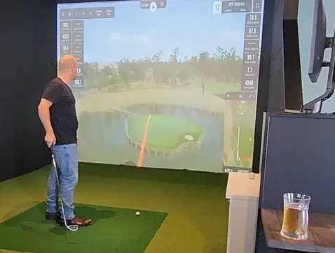 Man playing on golf simulator at Napier sprts bar.webp