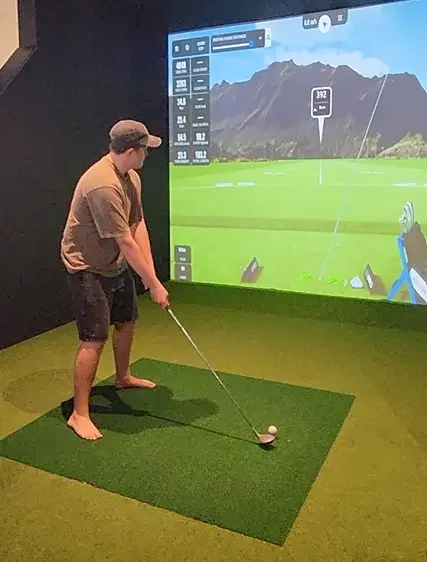 Young man lining up a shot on the golf sim at Good Sport sports bar Napier.webp