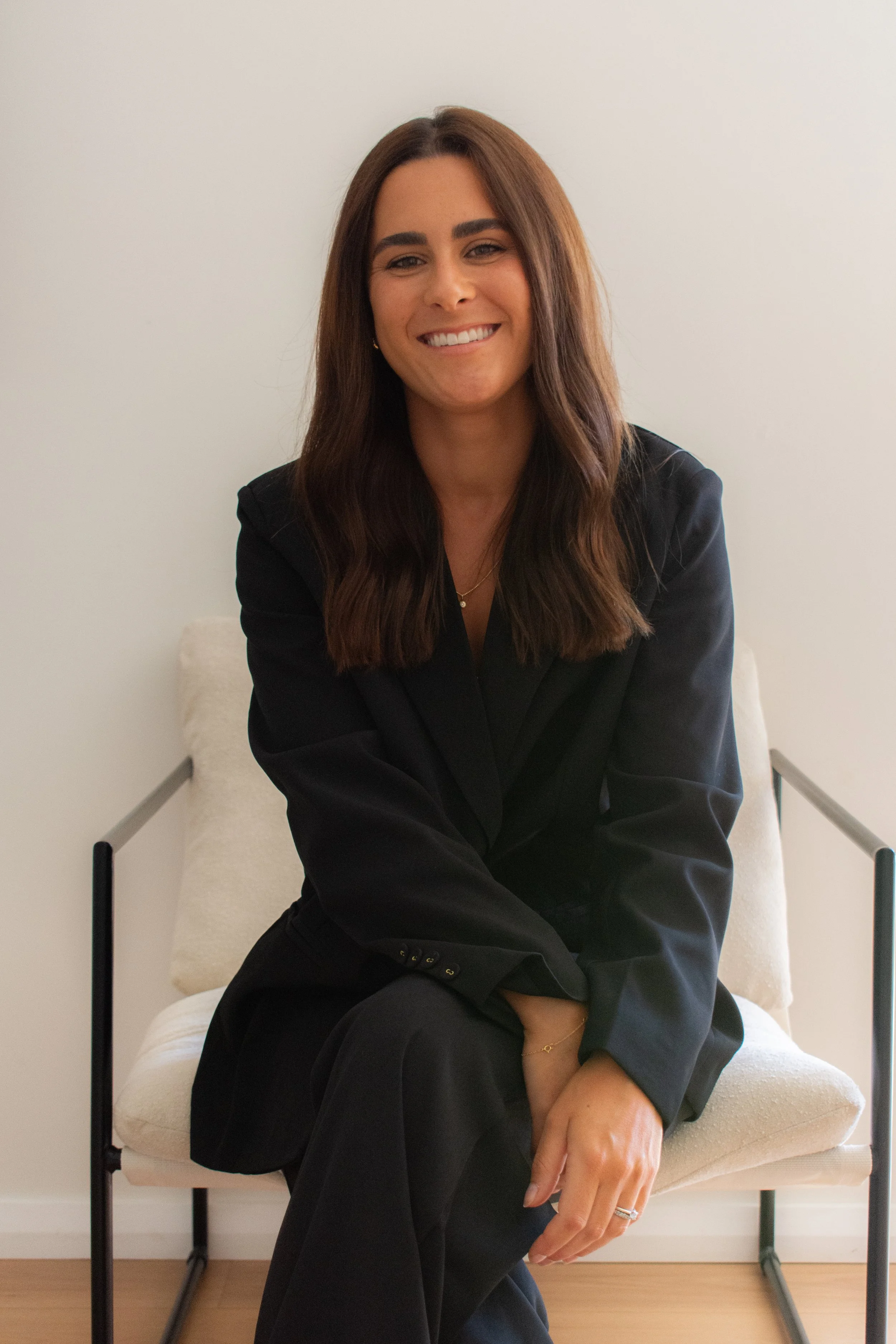 Brown hair girl smiling on chair in business suit
