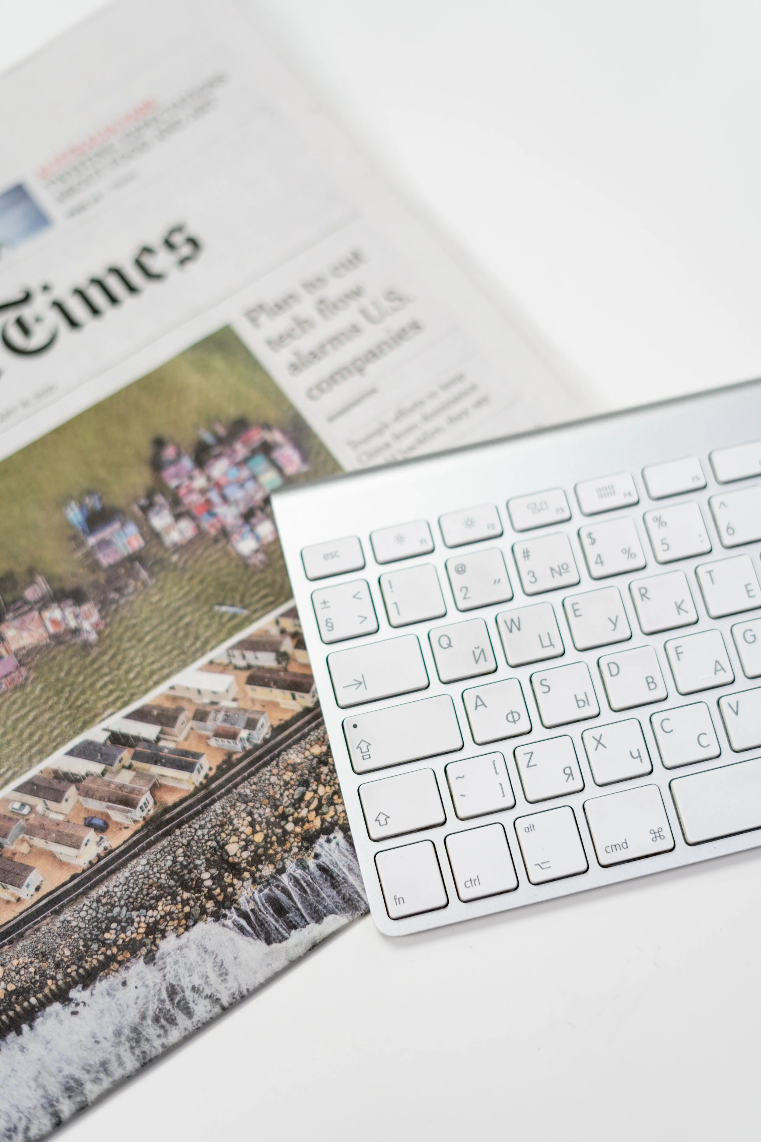 Front page of newspaper underneath a silver Apple keyboard