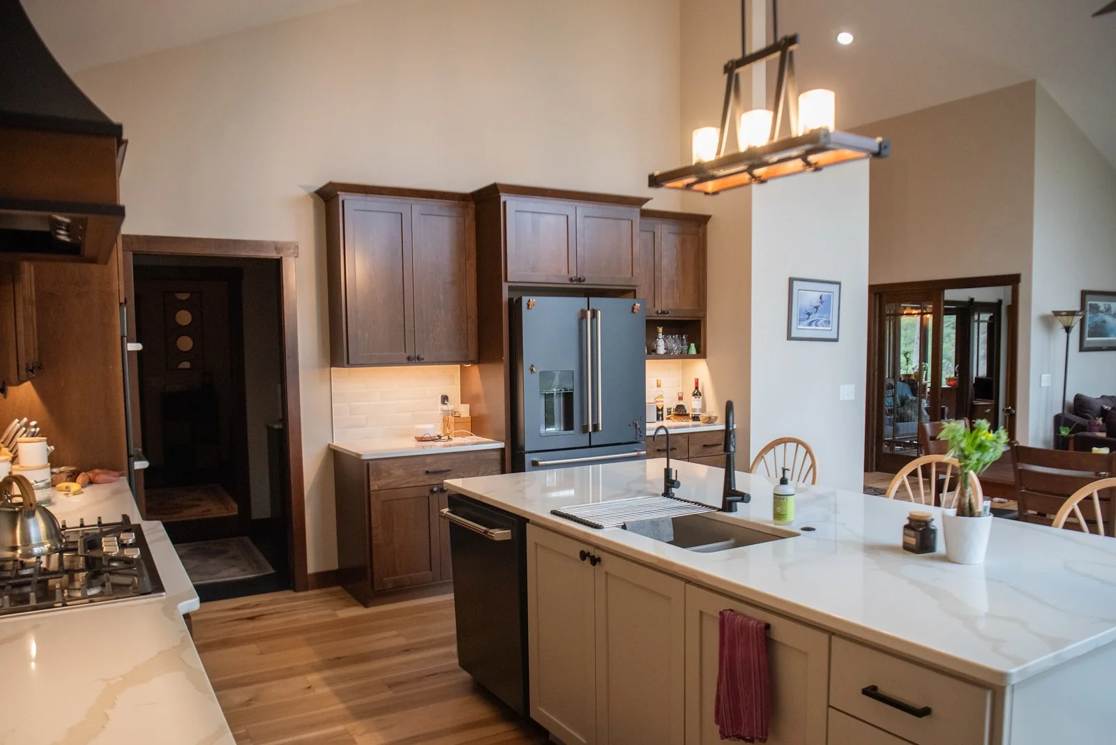 Warm, modern kitchen with large island, quartz countertops, wood cabinetry, stainless steel appliances, and pendant lighting