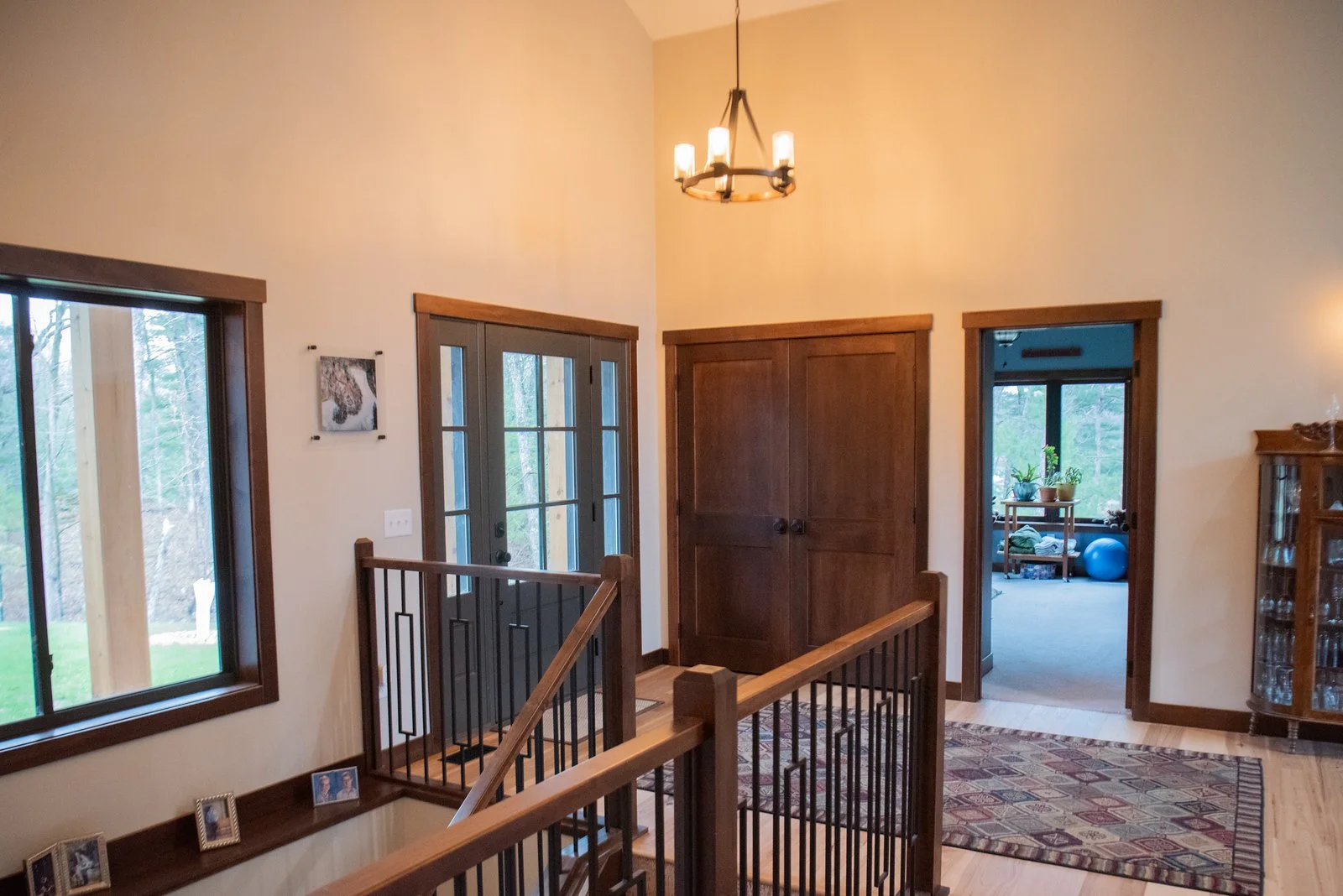 Home entry and stair landing with wood trim, double doors, chandelier lighting, and open views to adjacent rooms.