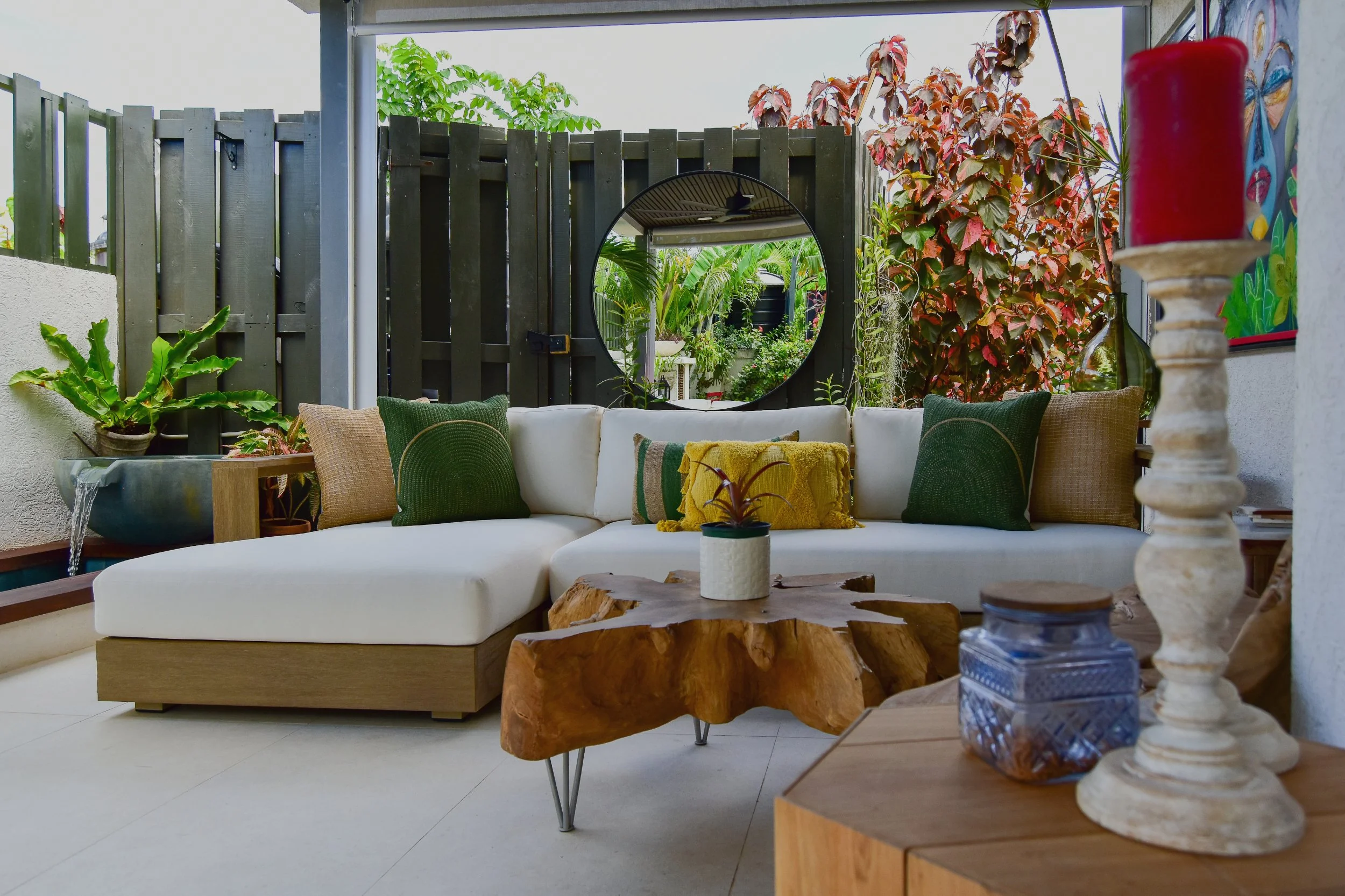 Modern outdoor living space with sectional sofa, tropical plants, water feature and natural wood accents in Ocho Rios, Jamaica – designed by AurumScape