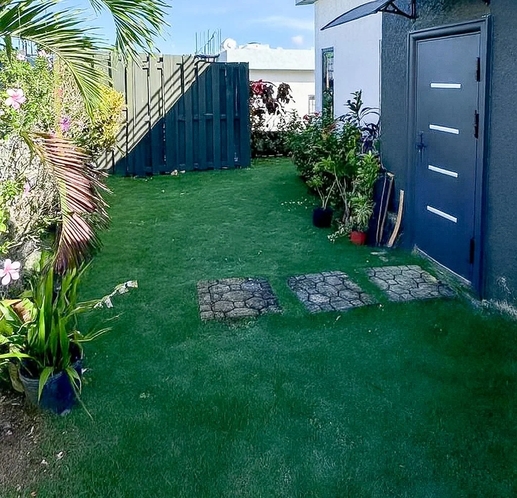 Backyard with grass and few step stones before landscaping design transformation.