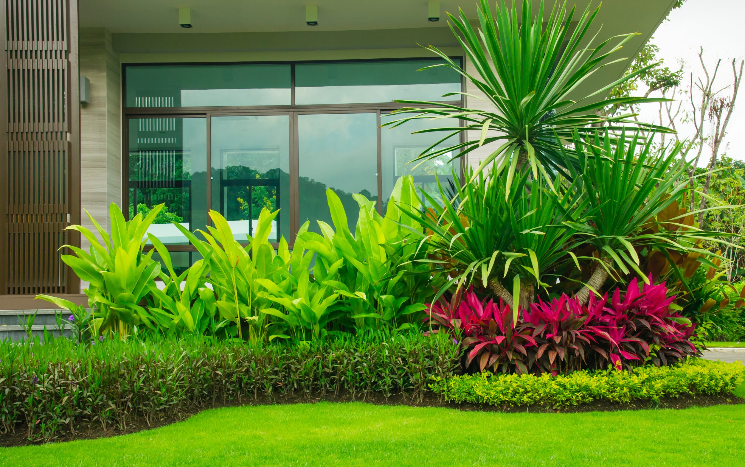 Beautifully designed backyard landscaping with table and chairs, grass, flowers and bamboo