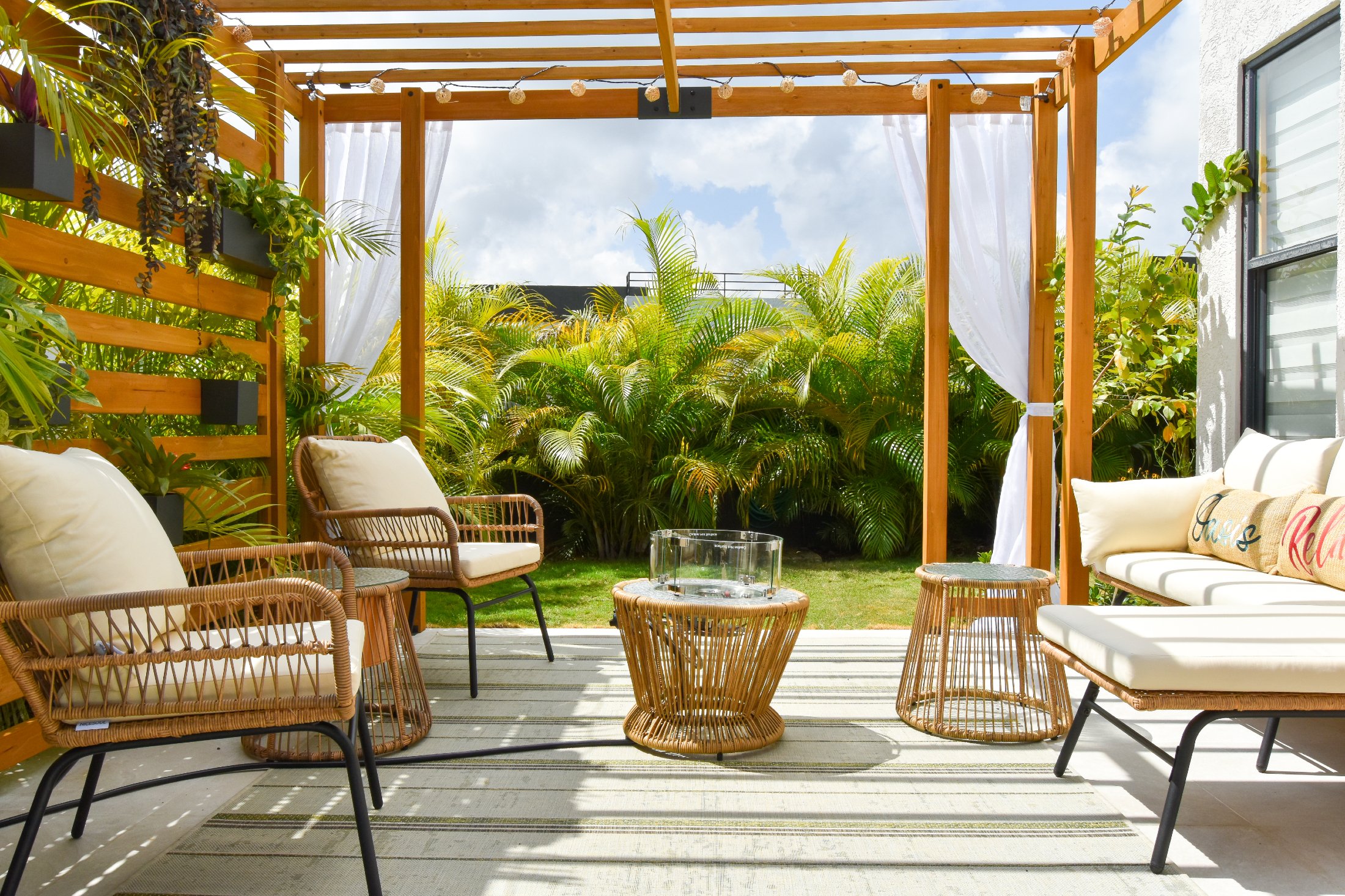 Modern outdoor furniture arrangement featuring woven lounge chairs, cushioned seating, and a low coffee table