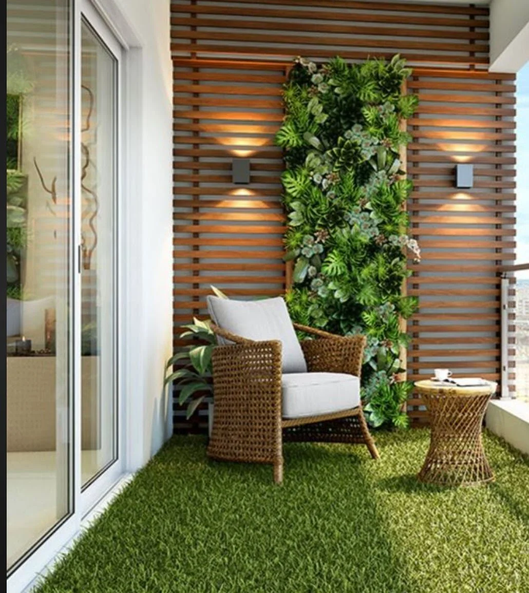 Modern balcony design featuring a lush vertical garden, wicker lounge chair, accent table, and artificial grass flooring, styled for outdoor living in Jamaica.