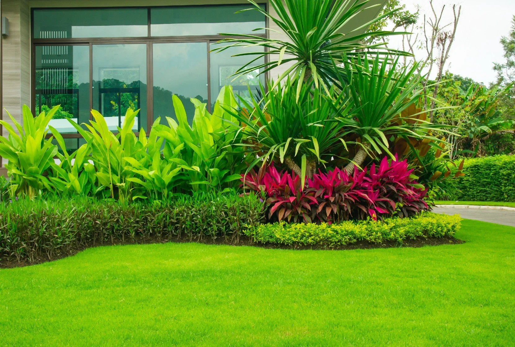Beautifully designed backyard landscaping with table and chairs, grass, flowers and bamboo