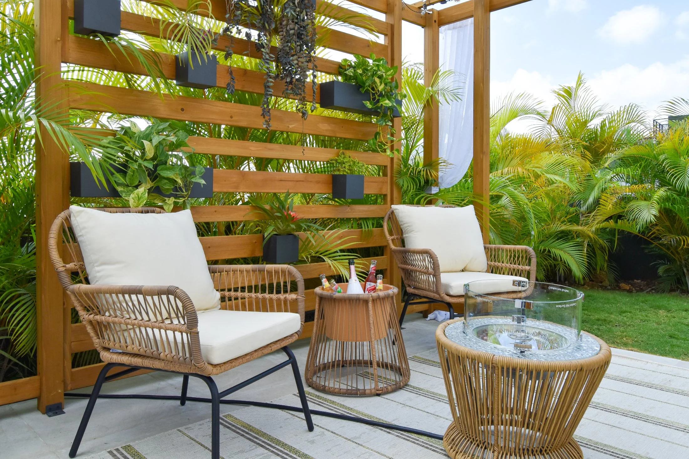 Modern outdoor seating area with woven lounge chairs, vertical garden wall, and pergola in a luxury Jamaican landscape design