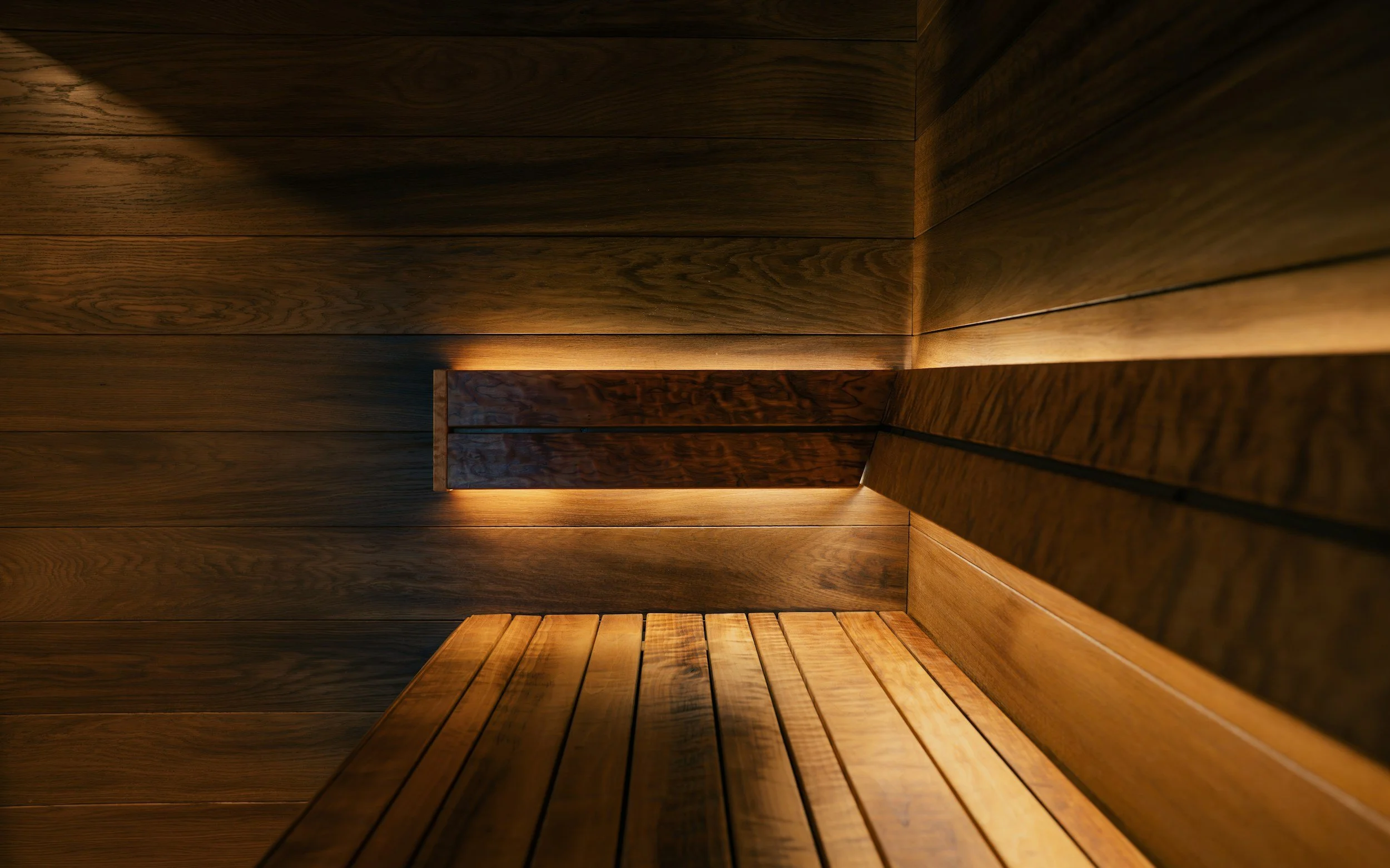 Interior of a sauna with wooden walls and seating, illuminated by soft lighting.