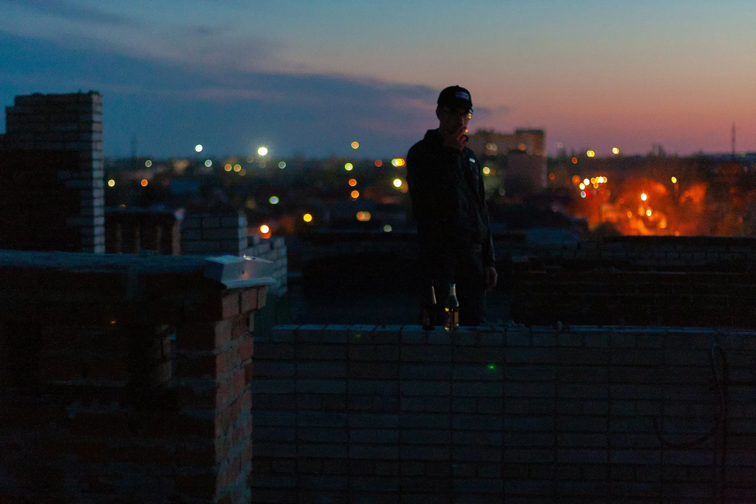 Man standing on a city rooftop at dusk