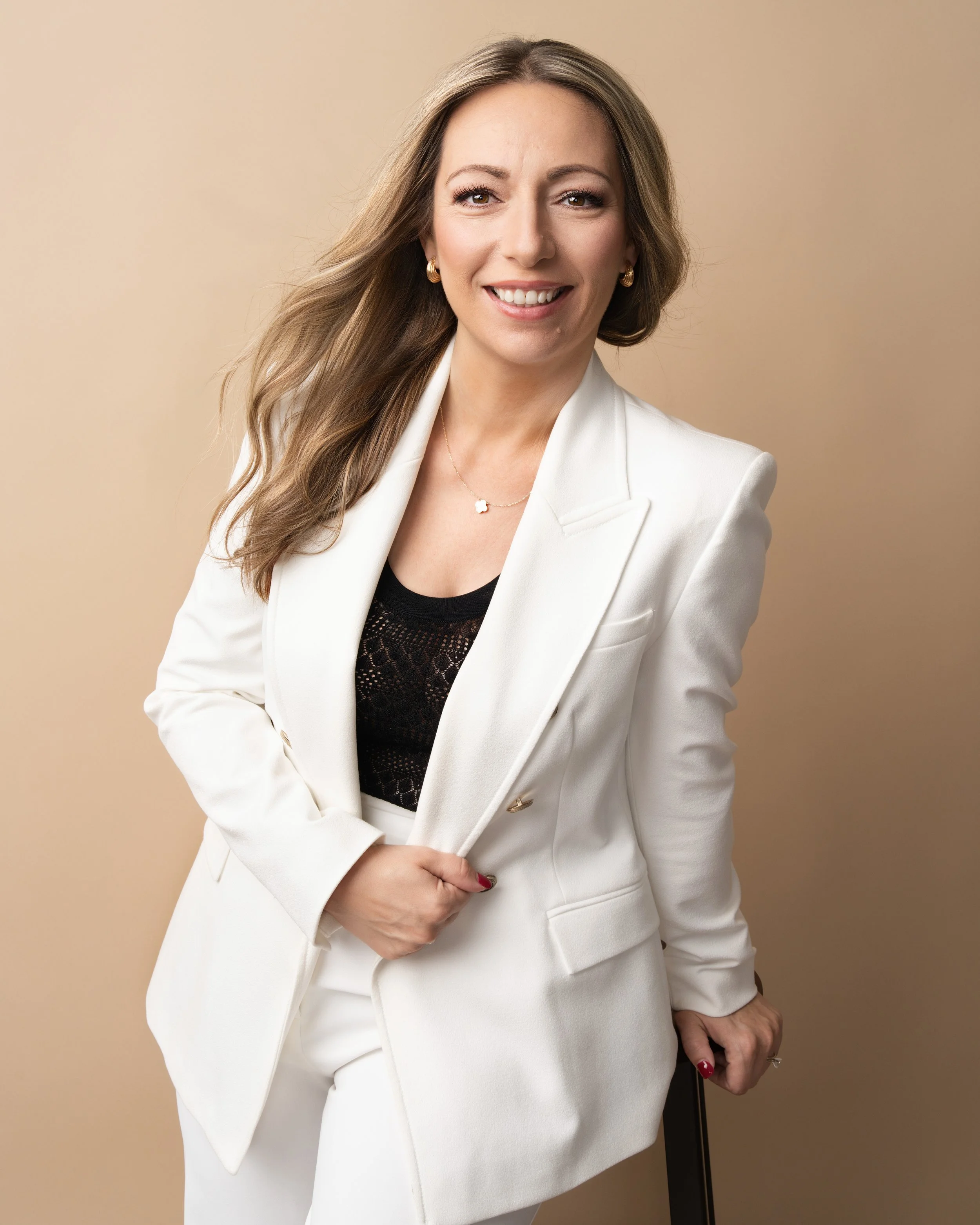 Woman in a white suit photographed on a neutral backdrop during a professional branding and headshot session in Orlando, Florida.