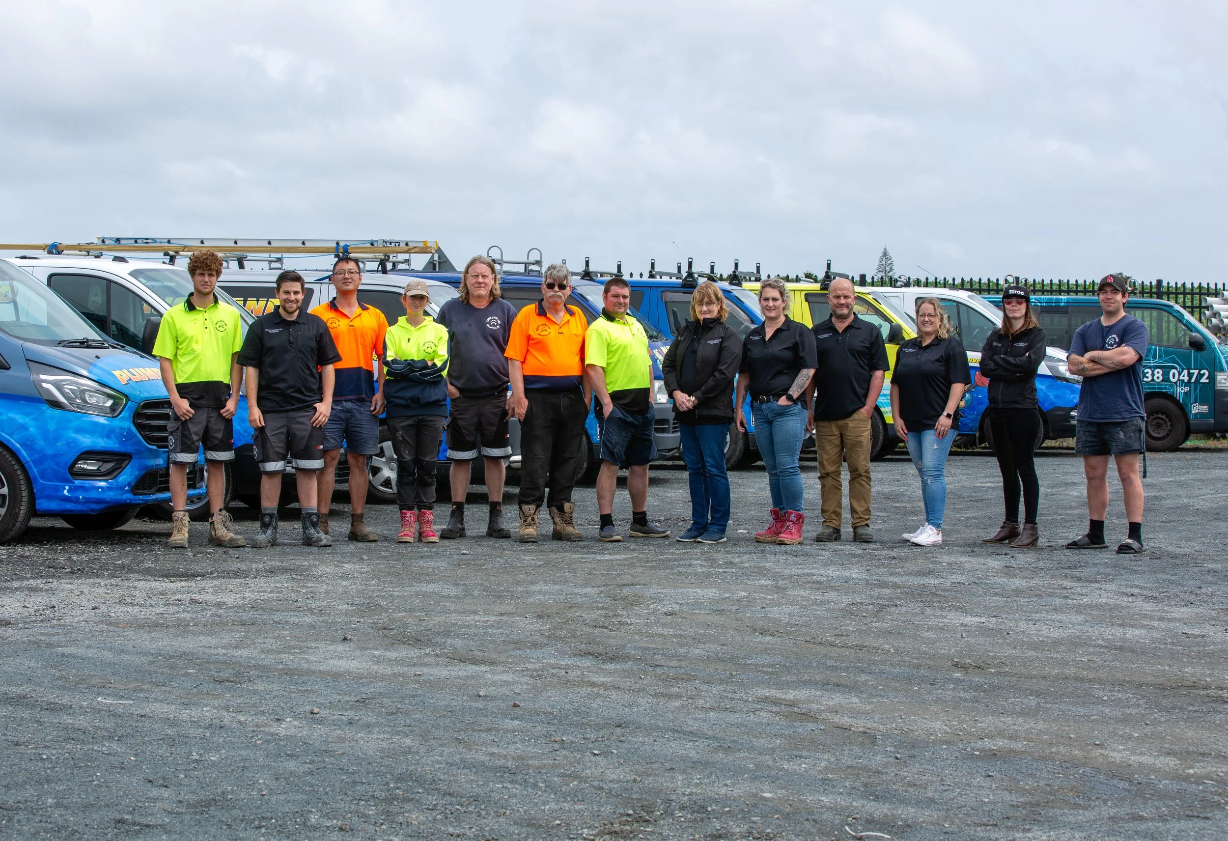 Grantham Group team of people standing in front of service vehicles on a gravel surface with a cloudy sky overhead.
