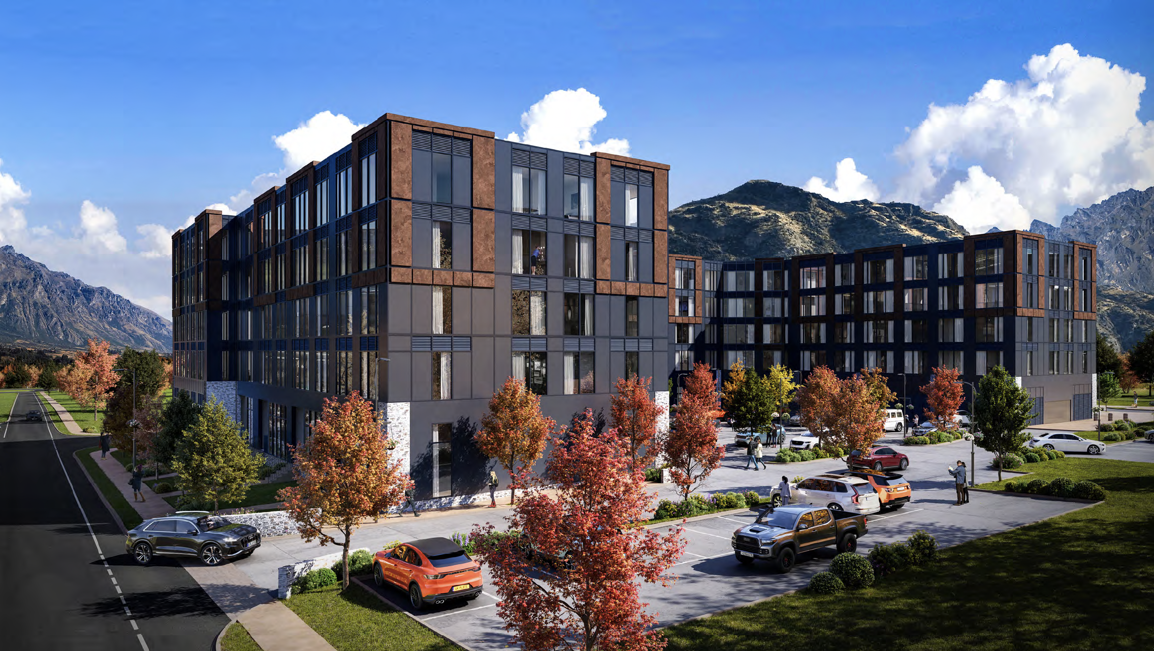 Modern apartment building with colorful fall trees, parking lot, and mountain landscape in the background. Grantham Group Project