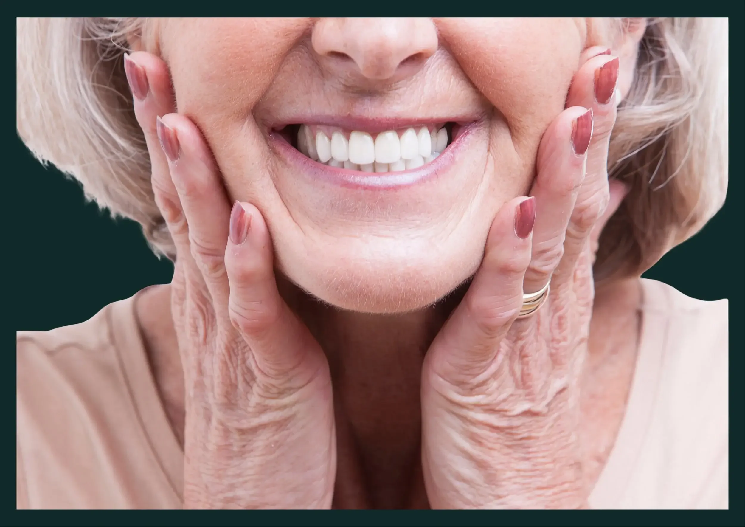 Close-up of an elderly woman with gray hair smiling, touching her cheeks with both hands