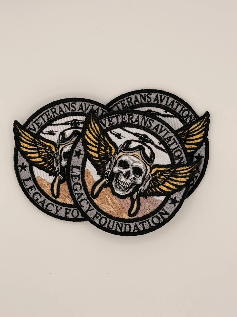 Stack of tan Veterans Aviation Legacy Foundation patches with skull and wing design representing courage, service, and flight legacy.