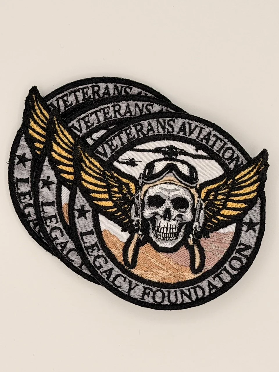 A stack of embroidered patches with pilot skull and wings from the Veterans Aviation Legacy Foundation overlapping to display detailed stitching.